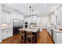 Bright, open kitchen featuring a large island, stainless steel appliances, and white cabinetry and hardwood floors at 3209 Bryant Falls Ct, Raleigh, NC 27613