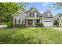 Charming two-story home with gray siding, black shutters, manicured lawn, and an attached two-car garage at 401 Clingstone Ct, Cary, NC 27519