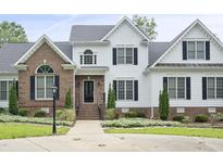 Charming two-story home featuring a mix of white siding and brick, with dark shutters and manicured landscaping at 4812 Cornoustie Ct, Holly Springs, NC 27540