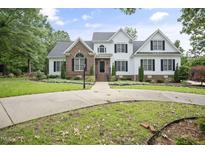 Beautiful two-story home with a manicured lawn, brick and siding accents, and a circular driveway at 4812 Cornoustie Ct, Holly Springs, NC 27540