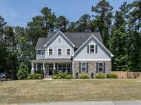 Charming two-story home with stone accents, manicured lawn, and lush landscaping at 497 Rockport Dr, Clayton, NC 27527