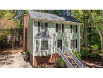 Charming two-story home with light green siding, black shutters, and landscaped front yard, creating great curb appeal at 6904 Sandringham Dr, Raleigh, NC 27613