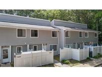 View of the townhouse featuring gray siding and a white picket fence in front of the property at 7407 Sandy Creek Dr, Raleigh, NC 27615