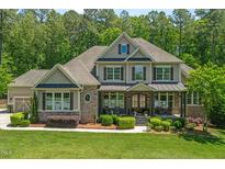 Charming two-story home with a manicured lawn, stone accents, and a welcoming front porch at 7544 Hasentree Club Dr, Wake Forest, NC 27587