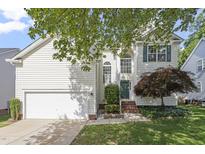 Charming two-story home featuring an attached garage, a manicured lawn, and mature landscaping at 8721 Springhouse Ln, Raleigh, NC 27617