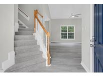 Inviting entryway with gray vinyl flooring, stairs, and a view into the living room with bright natural light at 8820 Waynick Dr, Raleigh, NC 27617