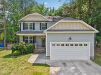 Charming two-story home with a manicured lawn and a welcoming front porch at 10504 Carsons Creek Dr, Zebulon, NC 27597