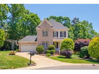 Charming two-story brick home with manicured lawn and lush landscaping under a clear blue sky at 10608 Thornbury Crest Ct Ct, Raleigh, NC 27614