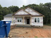 Exterior home view with covered front porch and double-hung windows amid construction and wooded backdrop at 13159 S Nc-231 Hwy, Middlesex, NC 27557