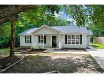Charming single-story home featuring a covered front porch, manicured landscaping, and black window shutters at 144 Holly Mountain Rd, Holly Springs, NC 27540
