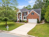 Charming two-story brick home featuring a well-manicured front yard and an attached two-car garage at 15 Aman Ct, Durham, NC 27713