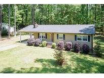 Charming single story home featuring a metal roof, well-maintained lawn, and mature trees in a quiet, wooded setting at 4221 River Run Dr, Sanford, NC 27332
