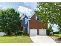 Inviting two-story brick home with a well-manicured lawn, two-car garage, and blue accents at 5416 Whisperwood Dr, Durham, NC 27713