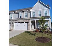 Charming two-story townhome featuring a two-car garage, stone accents, and a well-manicured lawn with beautiful landscaping at 646 Shelford Trl, Zebulon, NC 27597