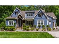 Charming blue two-story home with lush landscaping, covered porch, and stone accents at 7116 Dumfries Ln, Chapel Hill, NC 27514