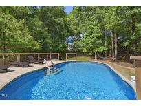 Inviting backyard pool with sun deck and surrounded by mature trees providing shade and privacy at 7824 Hemlock Ct, Raleigh, NC 27615