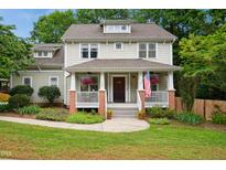Charming two-story home with a welcoming front porch, manicured landscaping, and an American flag at 1102 Whiston Dr, Apex, NC 27502