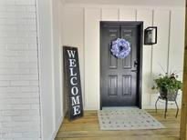 Charming front door with a floral wreath, wooden welcome sign, and quaint farmhouse lighting at 116 Lumpkin St, Raleigh, NC 27610