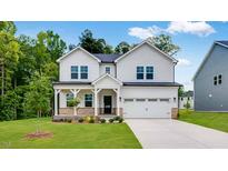 Two-story home with white siding, a covered porch, and an attached two-car garage on a green lawn at 174 Hickory Grove Dr, Sanford, NC 27330