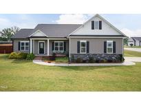 Charming single-story home boasts a manicured lawn and inviting covered porch at 18 Fisher Rd, Lillington, NC 27546