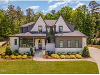 Beautiful two-story home featuring a landscaped yard, gray trim, and a striking front entrance with a glass door at 2016 Falls Forest Dr, Raleigh, NC 27615