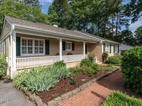 Charming tan home with a covered porch and a beautifully landscaped front yard at 2143 Ridge Rd, Raleigh, NC 27607