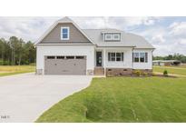 Charming single Gathering home with a 2-car garage, white siding, a covered porch and green grass at 24 Sanders Farm Dr, Smithfield, NC 27577
