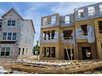 A new construction home with exposed framing, sheathing, and stacked lumber, ready for the next phase of building at 335 Chesapeake Cmns St # 107, Garner, NC 27529