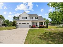 Charming two-story home boasts a well-manicured lawn, attached garage, and inviting front porch at 3409 Lemon Springs Rd, Sanford, NC 27332