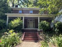 Charming two-story brick home featuring a welcoming front porch with classic columns and lush landscaping at 404 Kinsey St, Raleigh, NC 27603