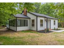 Charming one story home with a brick chimney, black roof, large front windows, and a well landscaped yard at 4713 Erwin Rd, Durham, NC 27705