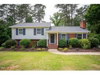 Charming two-story home features a blend of siding and brick, complemented by dark shutters and lush landscaping at 4813 Glen Forest Dr, Raleigh, NC 27612
