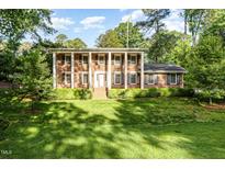 Two-story brick home with white columns, black shutters, and a well-manicured lawn at 5513 Parkwood Dr, Raleigh, NC 27612