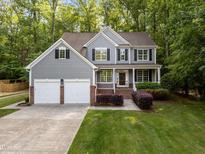 Two-story home featuring gray siding, black shutters, two-car garage, and a lush green lawn at 606 Churton Grove Blvd, Hillsborough, NC 27278