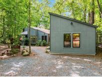 Charming exterior of a home surrounded by lush greenery and trees, with a gravel driveway at 61 Stone Ledge, Pittsboro, NC 27312