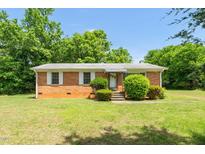 Charming single-story brick home featuring a well-maintained lawn and mature trees at 714 W Mckinley St, Mebane, NC 27302