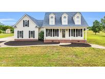 Charming home featuring a welcoming front porch, black shutters, and manicured landscaping at 750 James Norris Rd, Angier, NC 27501