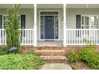 Charming blue front door with sidelights and brick steps leading to a welcoming porch at 7805 Tuscan Ridge Dr, Wendell, NC 27591