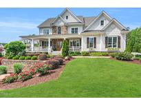 Stunning two-story home featuring a manicured lawn, stone accents, and a welcoming wrap-around front porch at 808 Wimberly Rd, Apex, NC 27523
