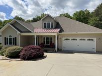 Charming one-story home with manicured landscaping, two-car garage, and inviting front porch with chairs at 84 Macbeth Ln, Roxboro, NC 27574