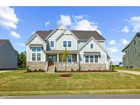 Beautiful two-story home featuring stone accents, light blue siding, and a welcoming front porch at 8416 Brady Pointe Rd, Fuquay Varina, NC 27526