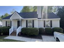 Inviting single-story home featuring fresh neutral siding, dark shutters, a well-manicured front lawn, and a cozy entryway at 106 Grange Dr, Wendell, NC 27591