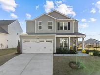 Charming two-story home with a two-car garage and well-manicured lawn under a blue sky at 1236 Shadow Shade, Wake Forest, NC 27587