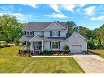 Charming two-story home with attached garage, well-manicured lawn, and inviting front porch at 128 Christy Ln, Dunn, NC 28334