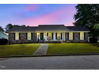 Charming brick home with a landscaped front yard and inviting front porch at dusk at 203 Marlowe Dr, Dunn, NC 28334