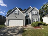 Charming two-story home with gray siding, an attached garage, and well-maintained landscaping at 204 Trevor Ridge Dr, Holly Springs, NC 27540