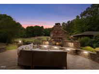 Inviting stone outdoor fireplace with seating area, perfect for entertaining in this serene backyard setting at 233 Hein Dr, Clayton, NC 27527