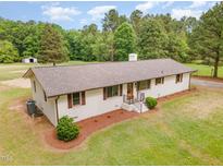 Beautifully landscaped ranch-style home with a lush green lawn and mature trees in a serene setting at 2712 Nc 57, Hillsborough, NC 27278