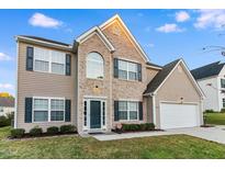 Charming two-story home features a brick facade, blue shutters, landscaped yard, and an attached two-car garage at 2902 Framer Ln, Durham, NC 27704