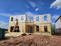 Two-story home under construction featuring wood framing, sheathing, and house wrap, set against a clear blue sky at 3007 Dog Rose Dr # 174, Durham, NC 27703